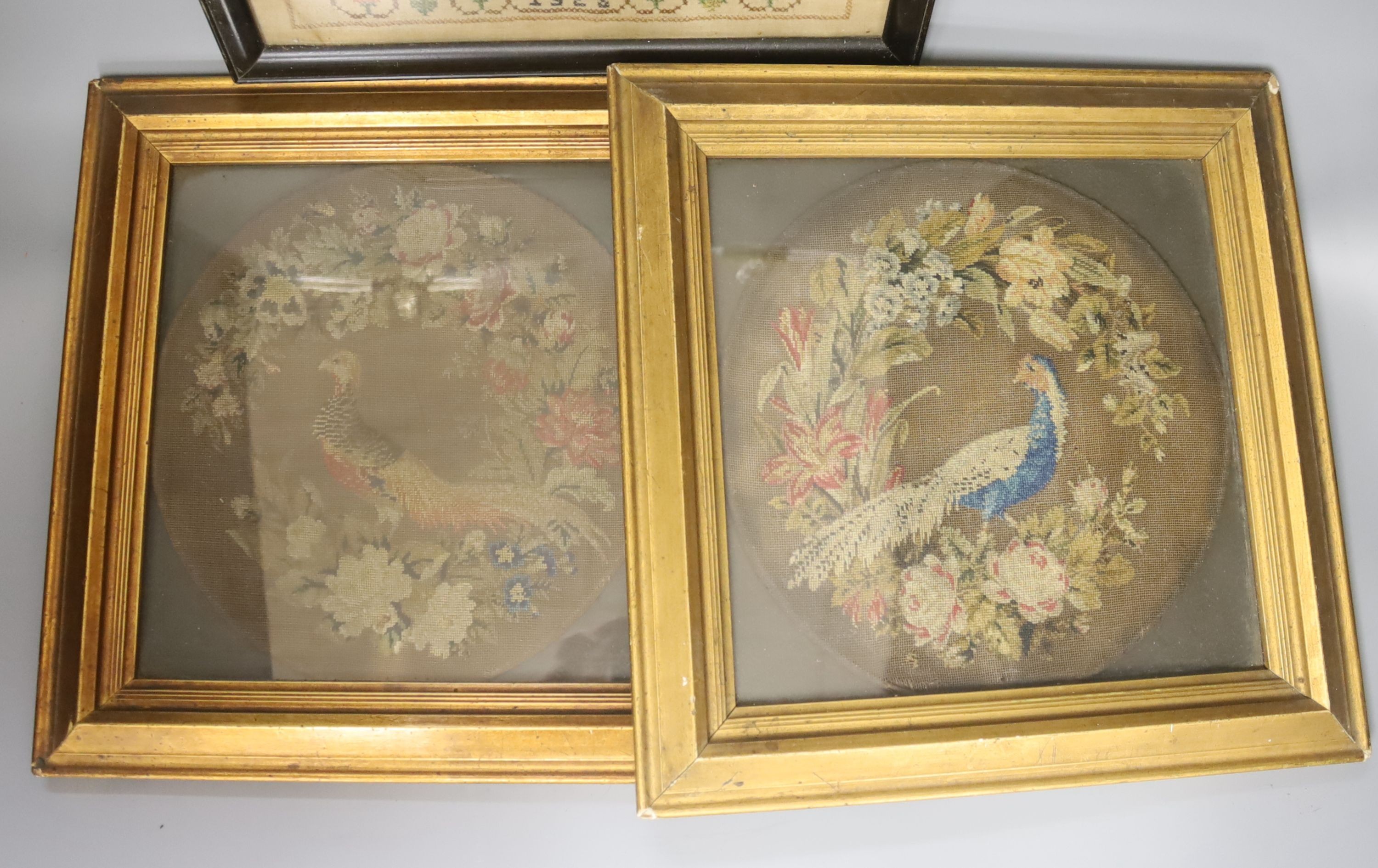 Pair of 19th century petit point face screens, a 1920s sampler and a heraldic panel, all framed.